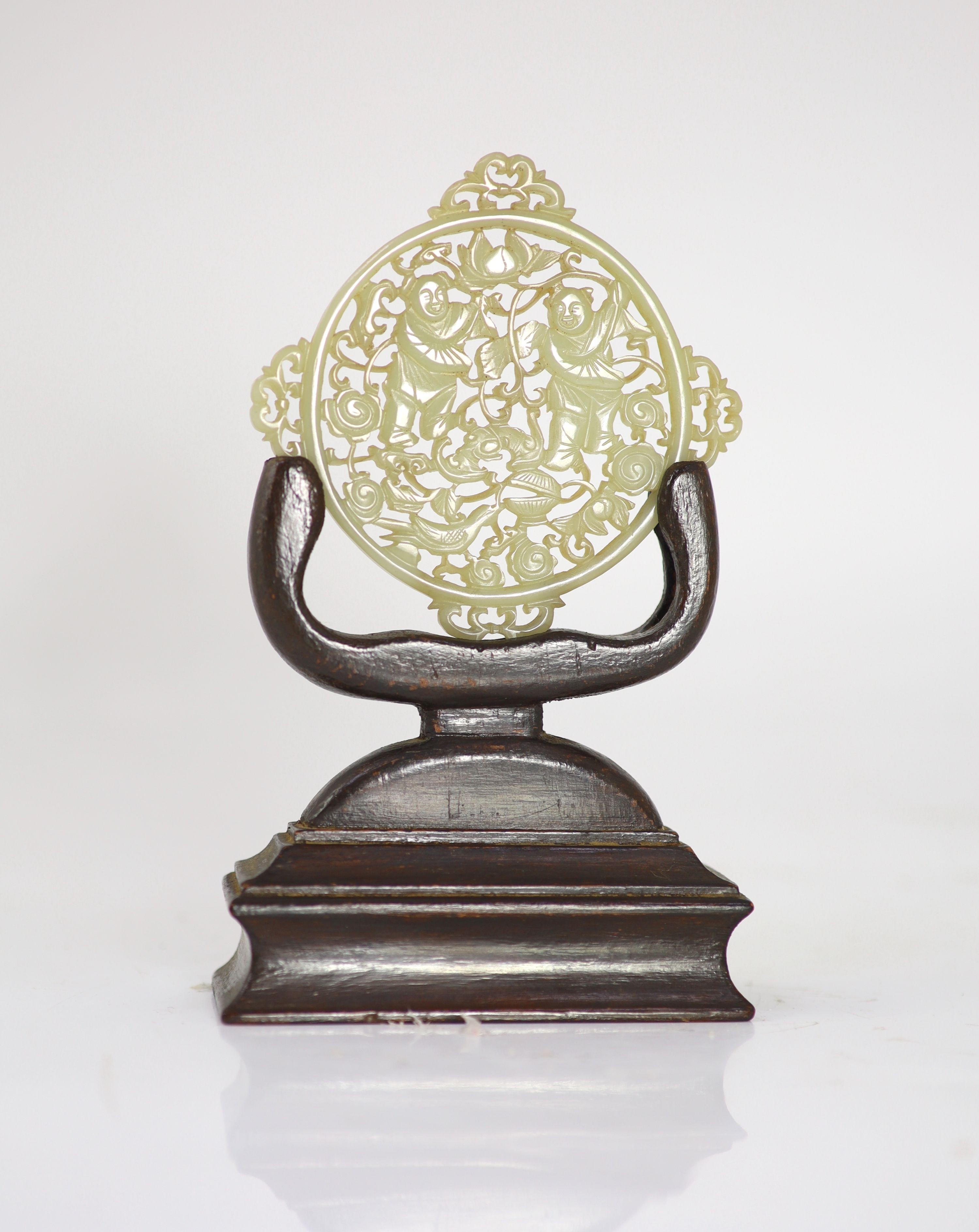 A Chinese pale celadon jade 'He He Erxian' shaped circular plaque, 18th/19th century, 9.5cm wide, wood stand